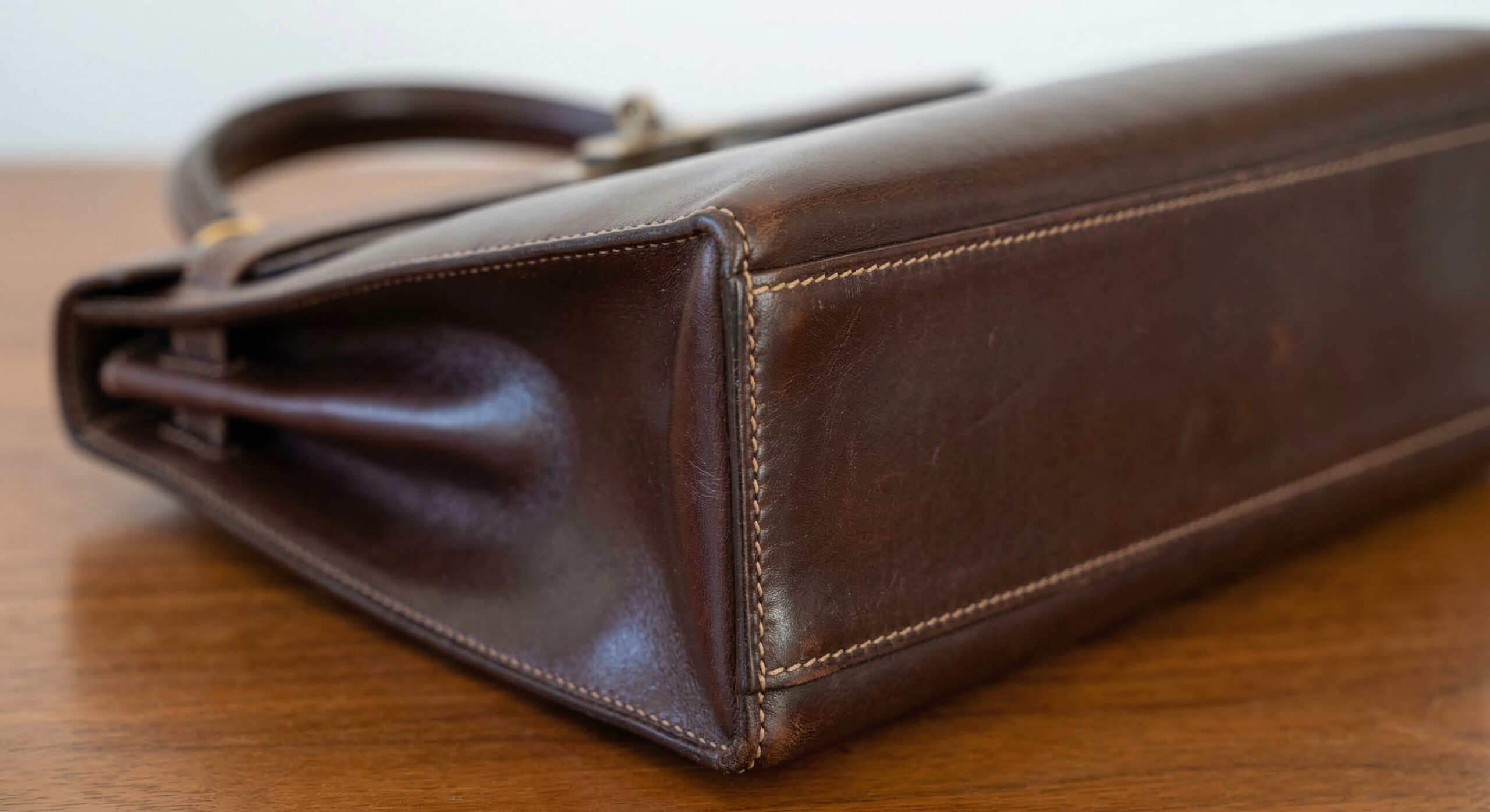 Close-up of Hermès Kelly bag sellier corner stitching in Box Calf leather showing patina development