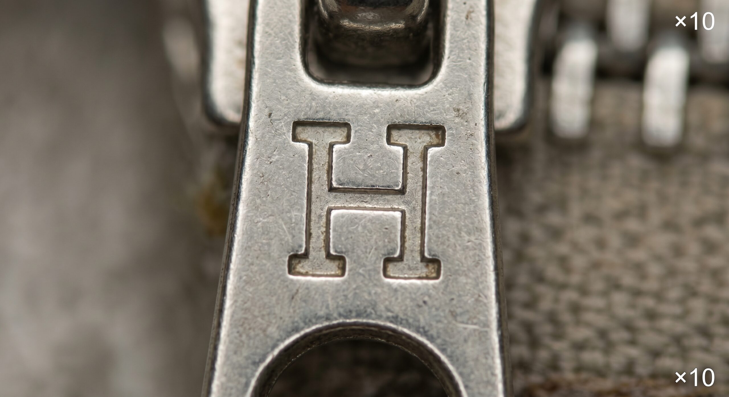 Hermes zipper pull engraving depth H character loupe authentication close-up