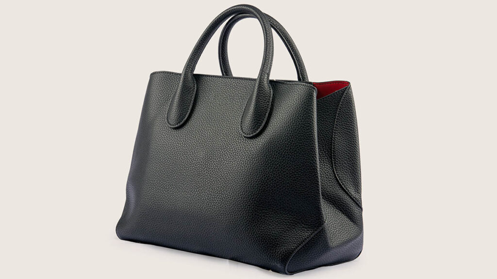 Structured black leather handbag presented as an anniversary gift, isolated on white