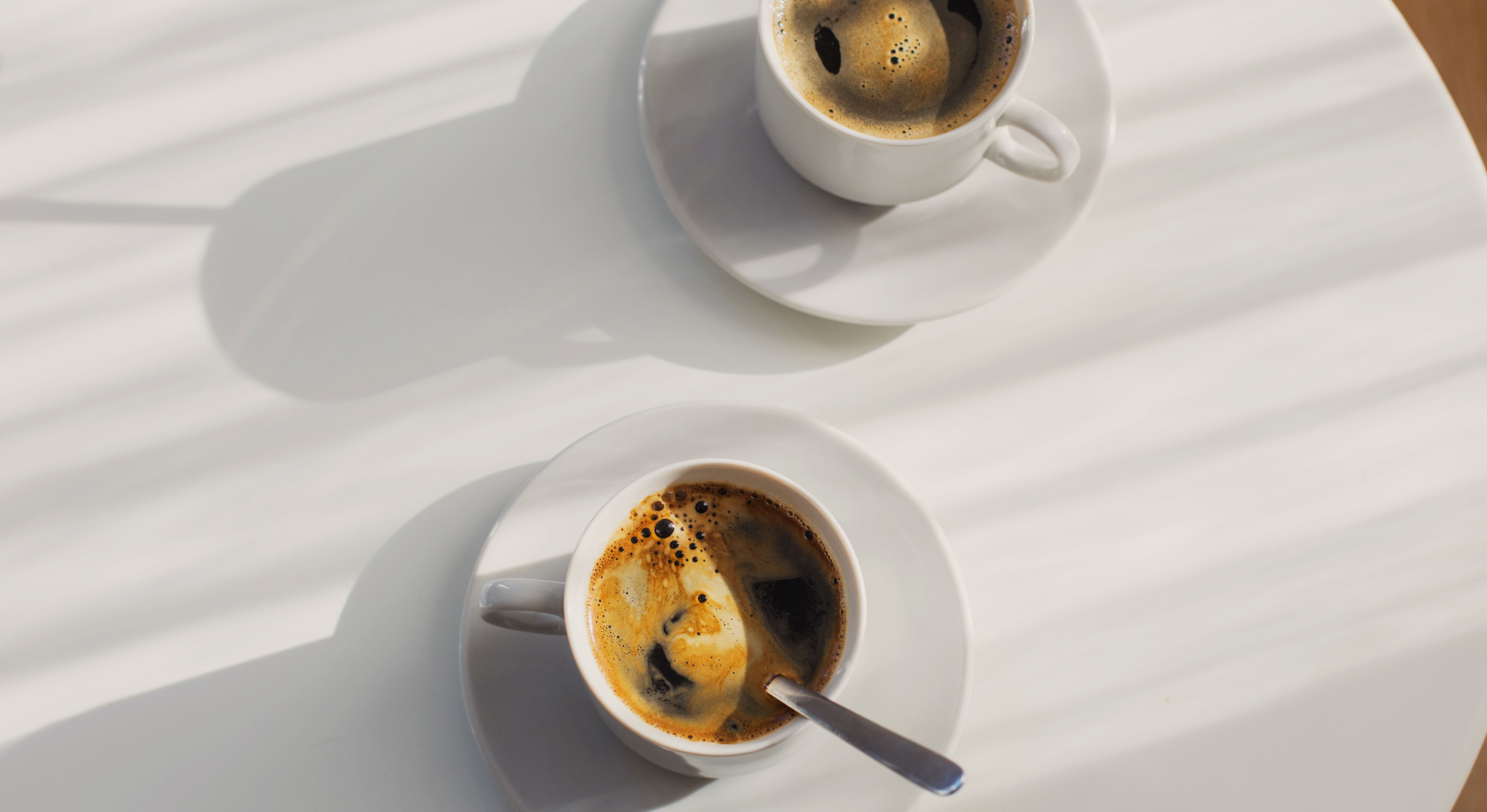 Two cups of coffee set on a table, representing the ongoing conversations that build a relationship with a sales associate
