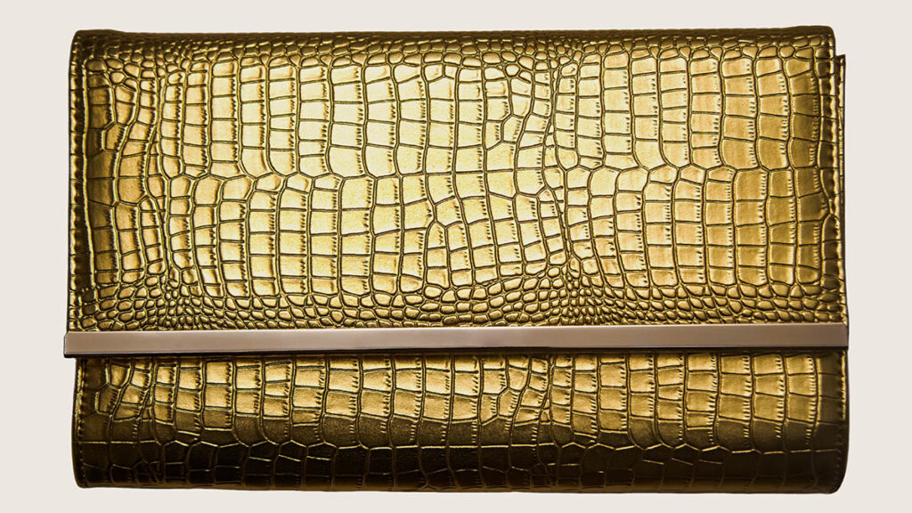 A small leather clutch shown as a product shot, representing the smaller accessories worth buying before a first Hermes bag