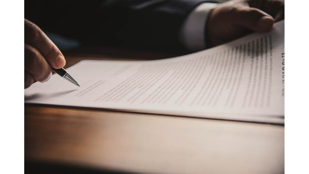 Hermès Bag Insurance: What Collectors Need to Know A hand signing an insurance document, representing the paperwork process collectors go through to insure a valuable bag