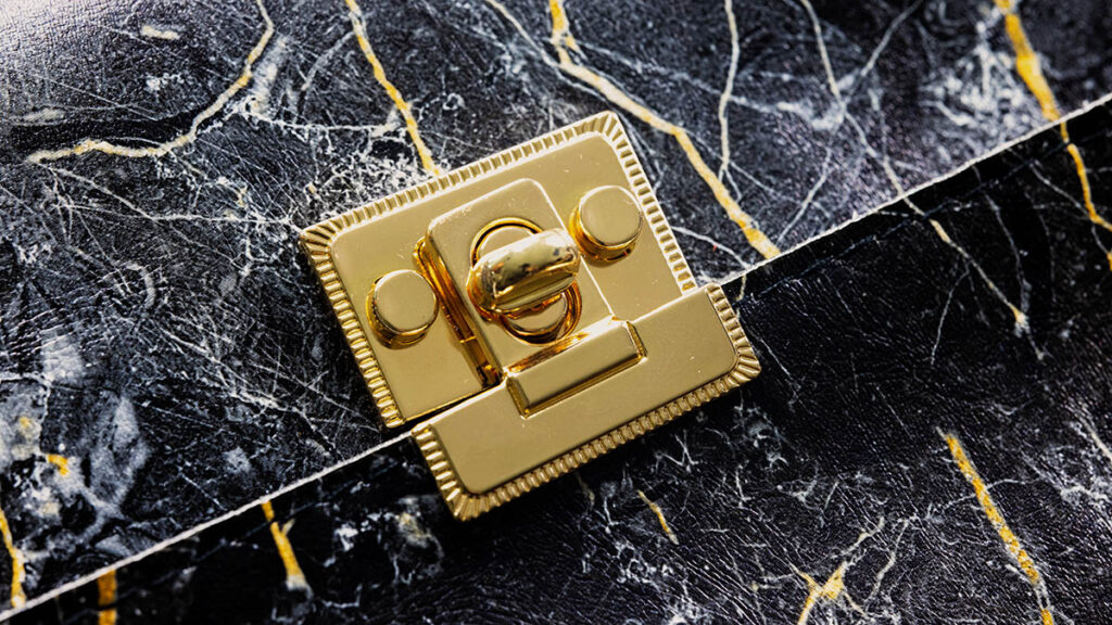 Sellier vs Retourne Kelly: How Structure Changes Leather Behaviour Close-up of a structured handbag lock and hardware, illustrating the rigid sellier construction compared with softer retourne Kelly bags
