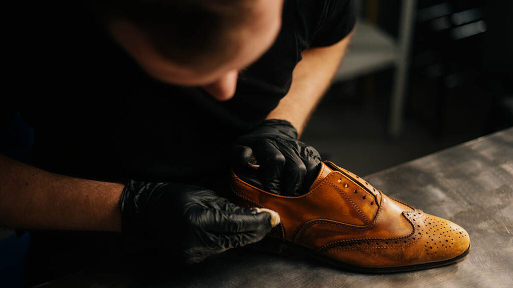 How Often Should You Condition Hermès Leather? Hands applying conditioner to leather with a soft cloth, illustrating how often Hermes leather genuinely needs conditioning