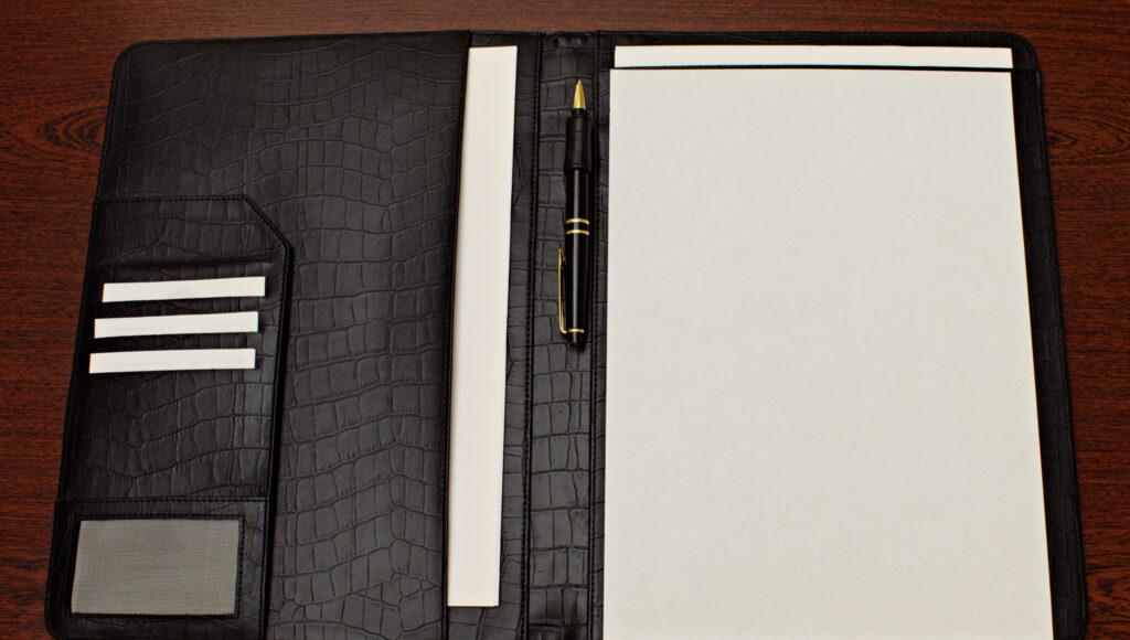 A leather folder with pen and notes, representing the paperwork and process behind a Hermes Special Order request