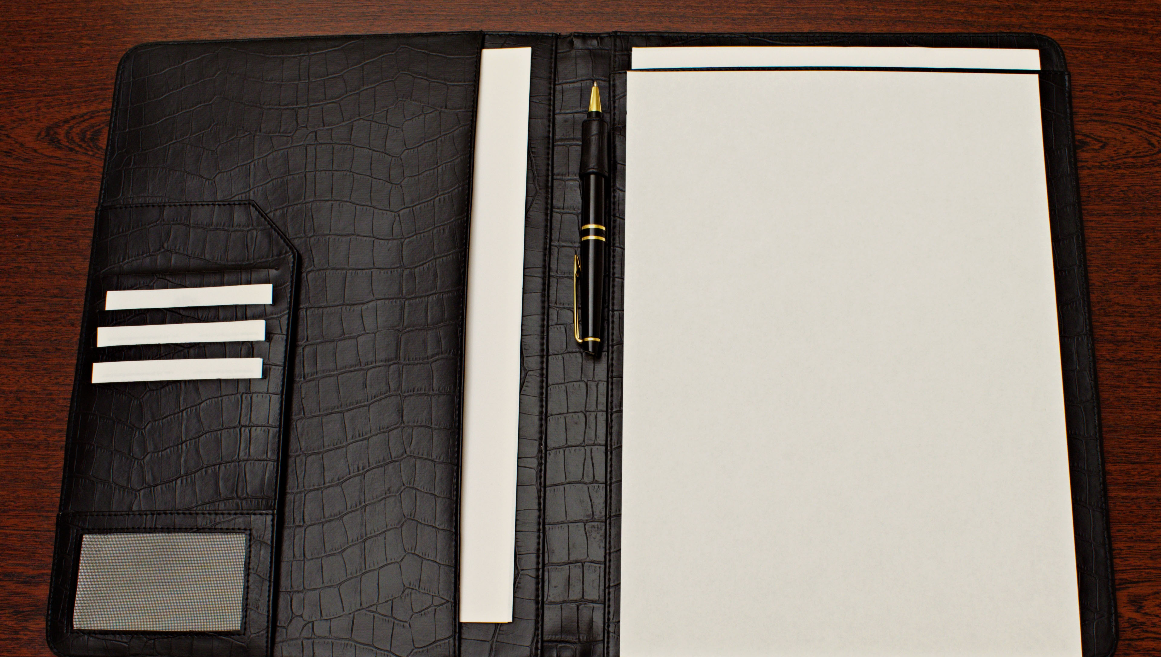A leather folder with pen and notes, representing the paperwork and process behind a Hermes Special Order request
