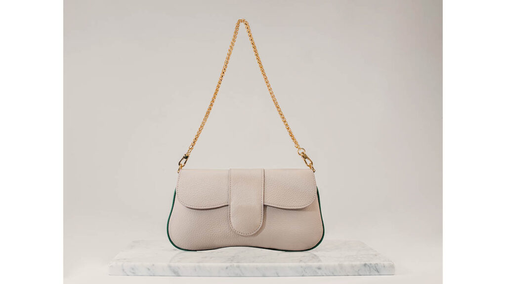 A luxury leather bag with a flap closure, representing the everyday wear behavior of the Hermes Roulis leather