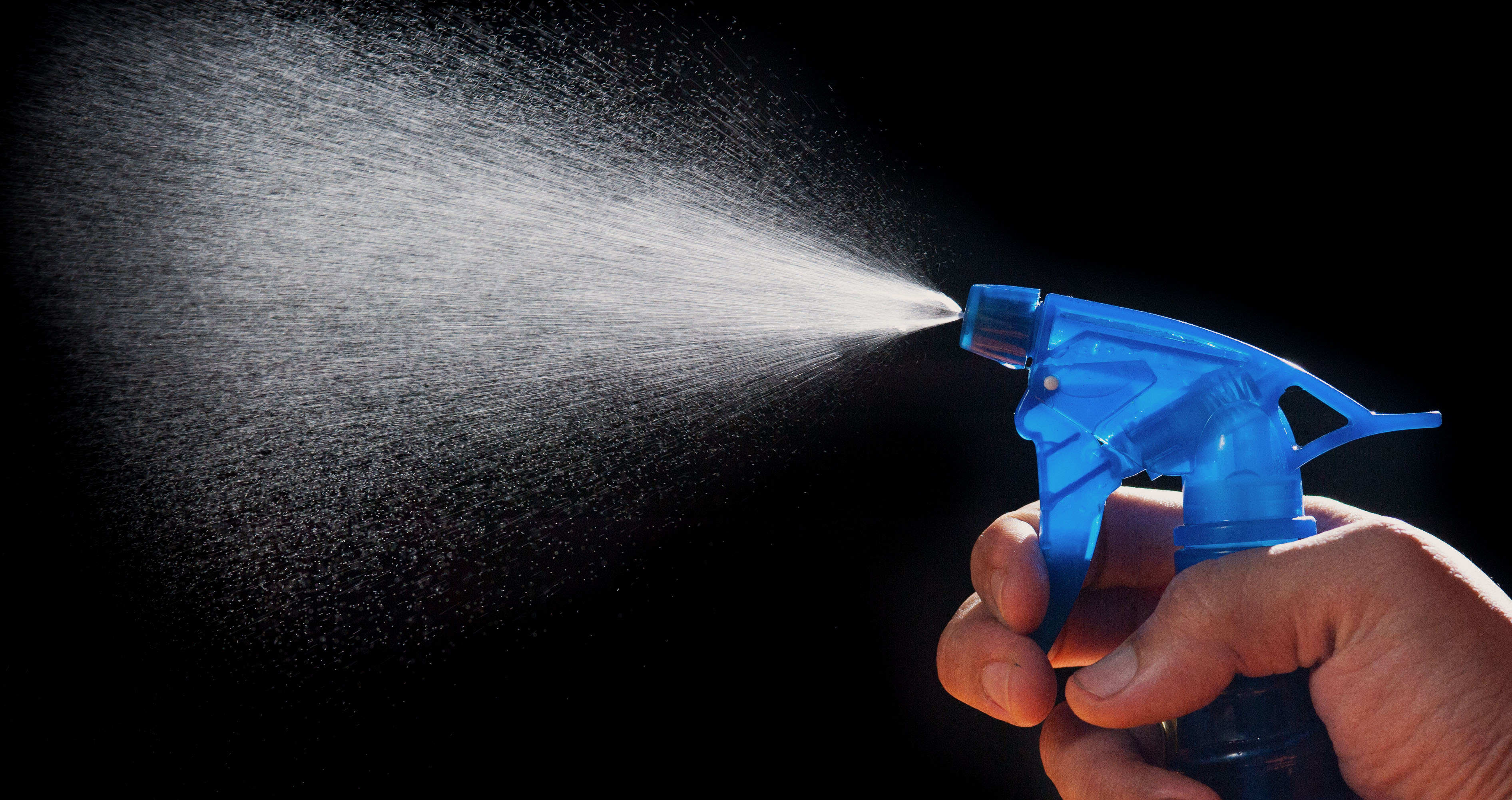 A fine mist sprayed from an atomizer bottle, representing the question of whether protectant spray is safe for Hermes leather