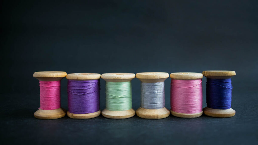 Rows of neatly matched sewing thread spools, illustrating the thread color consistency used to authenticate Hermes stitching