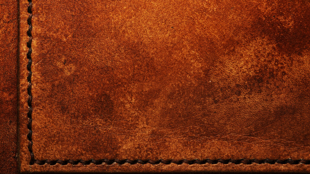 Macro close-up of hand-stitched leather with waxed thread on a wallet