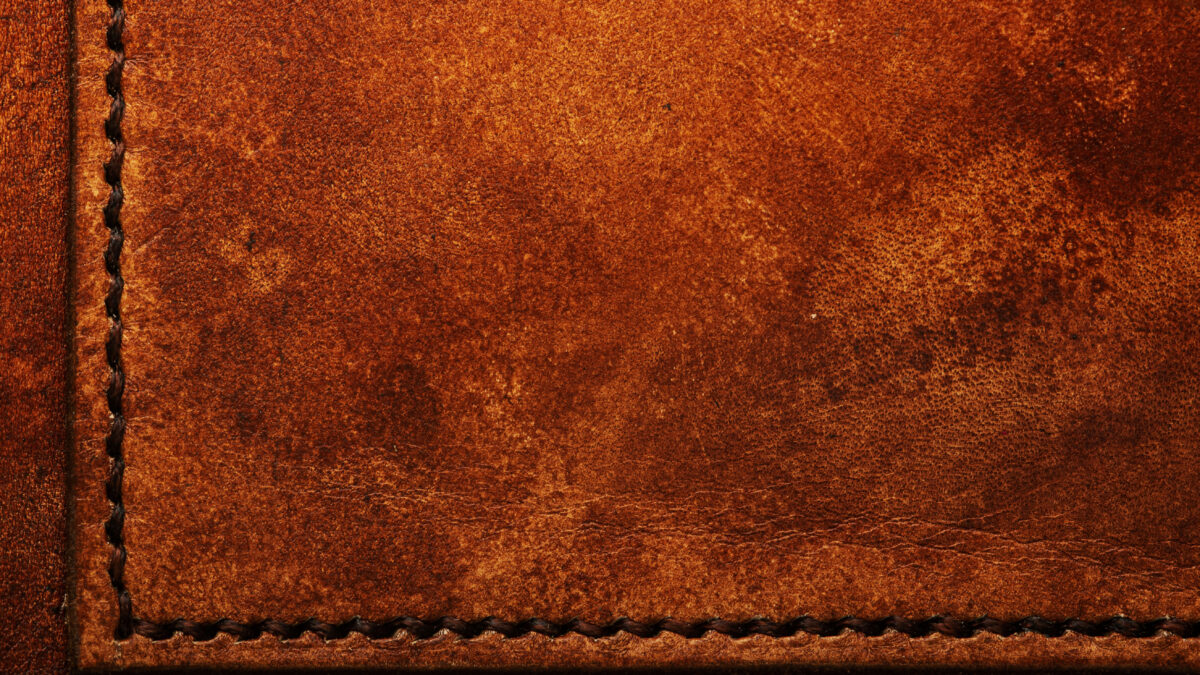 Macro close-up of hand-stitched leather with waxed thread on a wallet
